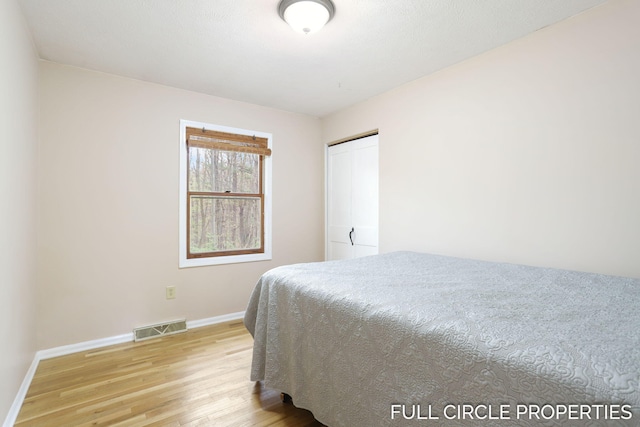 bedroom with light wood finished floors, baseboards, and a closet