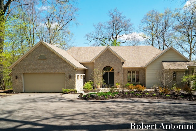 view of front of property featuring driveway, brick siding, and an attached garage
