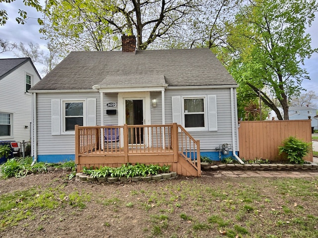 view of front of house featuring a chimney, roof with shingles, and fence