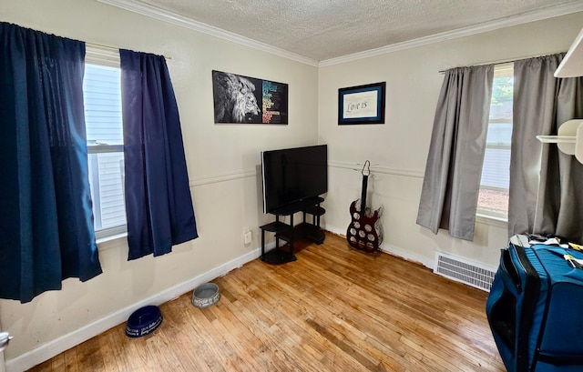 miscellaneous room featuring a textured ceiling, wood-type flooring, baseboards, and crown molding
