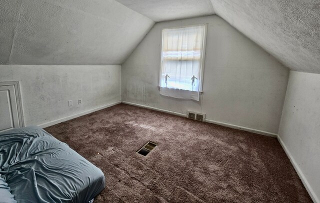 bonus room featuring a textured ceiling, lofted ceiling, carpet floors, and baseboards