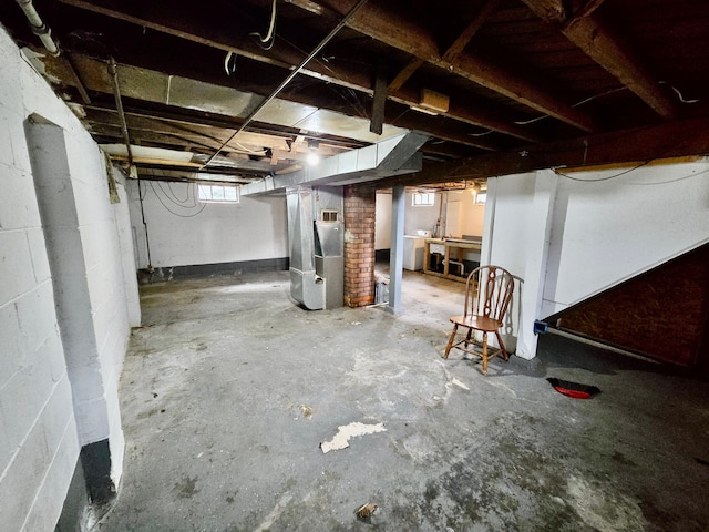 below grade area featuring heating unit and concrete block wall