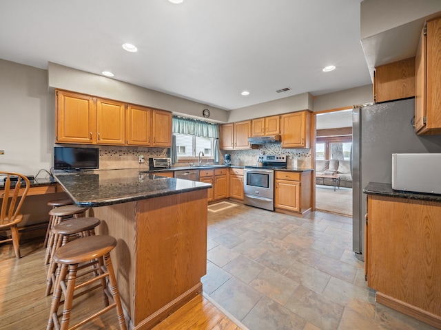 4825 Downing Dr, Pinckney, MI 48169 - kitchen with appliances with stainless steel finishes, a sink, decorative backsplash, a kitchen breakfast bar, and under cabinet range hood