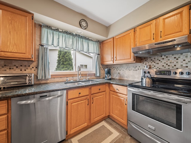 4825 Downing Dr, Pinckney, MI 48169 - kitchen with appliances with stainless steel finishes, a sink, under cabinet range hood, tasteful backsplash, and dark stone countertops