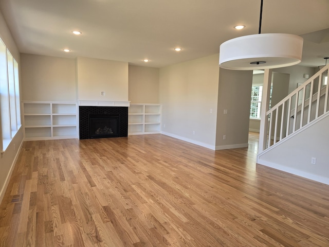 319 Sedgewood Ln, Ann Arbor, MI 48103 - unfurnished living room featuring light wood-style floors, recessed lighting, baseboards, stairs, and a tile fireplace