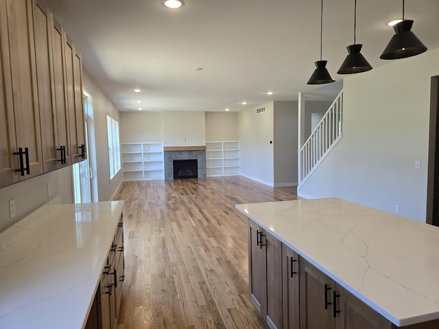 319 Sedgewood Ln, Ann Arbor, MI 48103 - kitchen with light wood finished floors, hanging light fixtures, built in shelves, recessed lighting, and light stone countertops