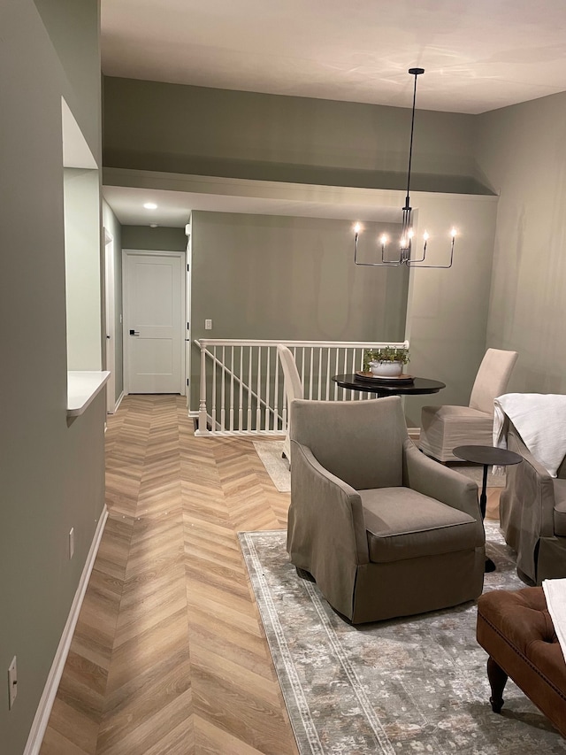 sitting room with a chandelier, baseboards, and an upstairs landing