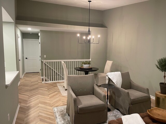 sitting room featuring a chandelier, baseboards, and an upstairs landing