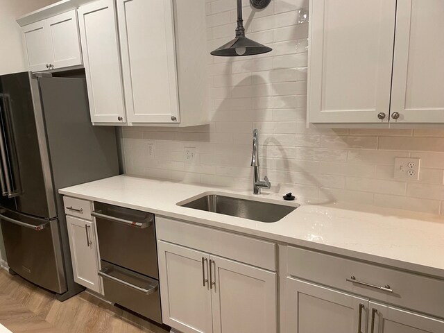 kitchen with a sink, freestanding refrigerator, dishwashing machine, and decorative backsplash