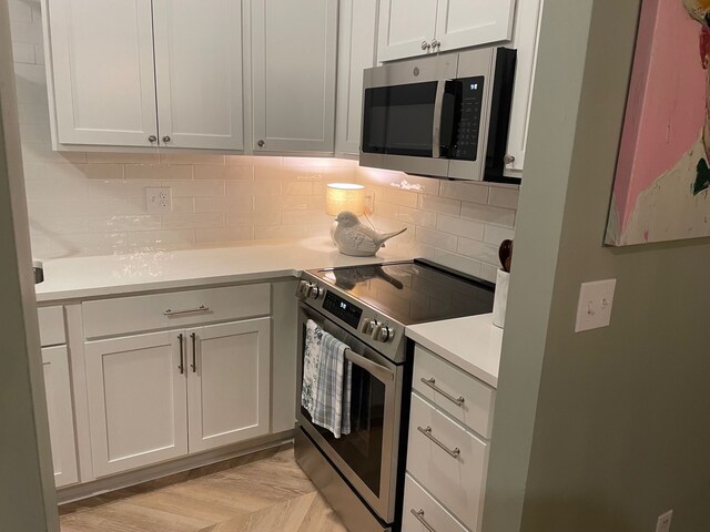 kitchen with stainless steel appliances, light countertops, decorative backsplash, and white cabinetry