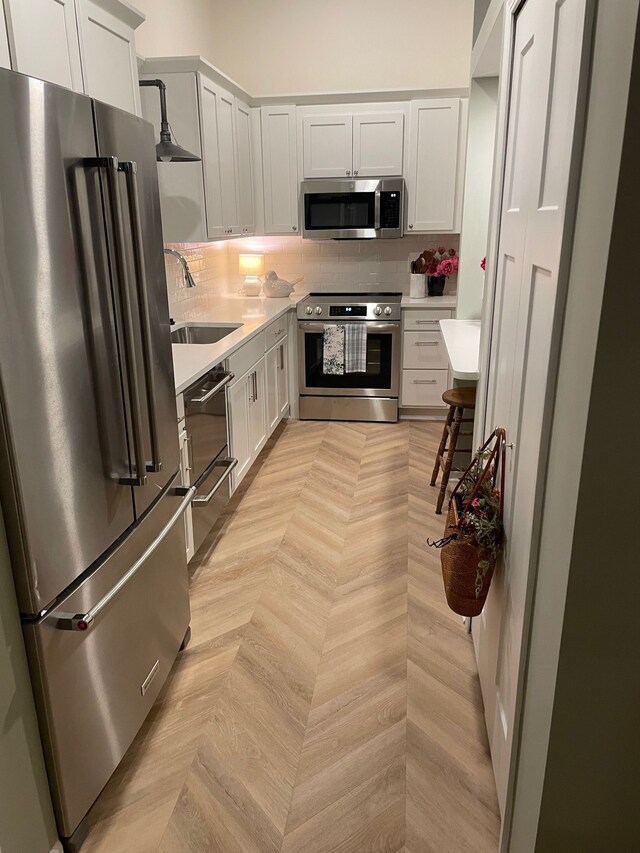 kitchen featuring stainless steel appliances, a sink, light countertops, and tasteful backsplash