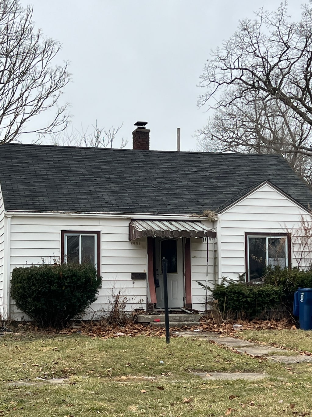 2631 Brownell Blvd, Flint, MI 48504 - view of front of property featuring a shingled roof, a chimney, and a front yard