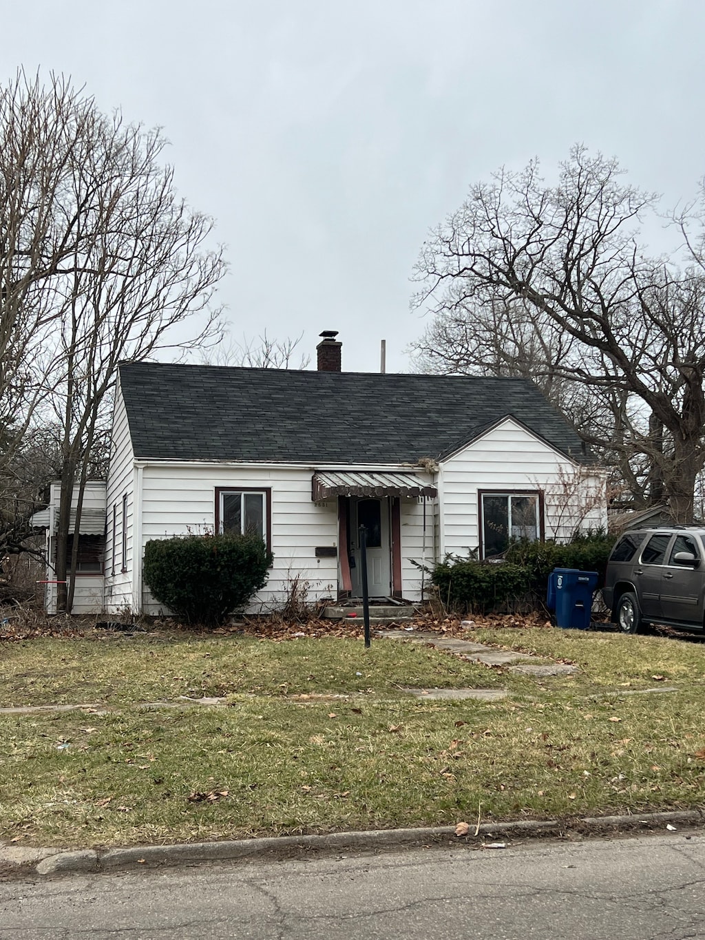 2631 Brownell Blvd, Flint, MI 48504 - view of front of property with a chimney, a front yard, and a shingled roof