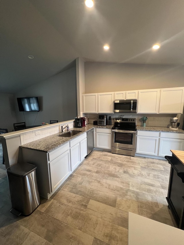 kitchen featuring stainless steel appliances, a sink, white cabinetry, high vaulted ceiling, and recessed lighting