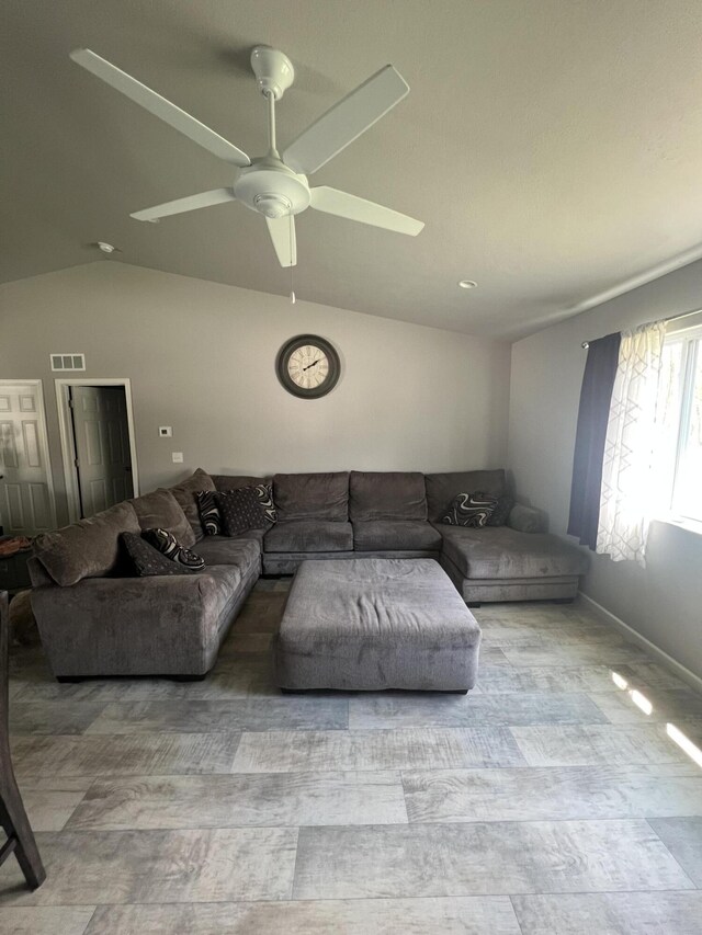 living room featuring vaulted ceiling, a ceiling fan, and baseboards