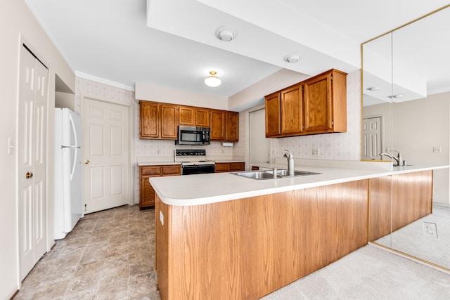 kitchen with electric stove, a sink, freestanding refrigerator, a peninsula, and brown cabinetry