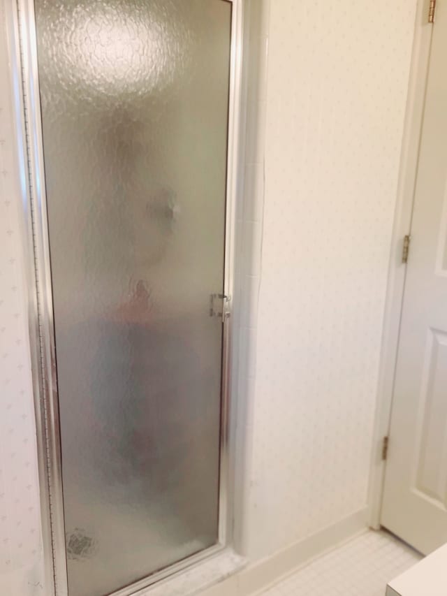 bathroom with wallpapered walls and a stall shower