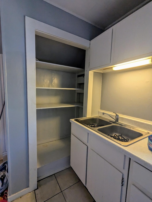 kitchen with light tile patterned flooring, white cabinetry, light countertops, and a sink