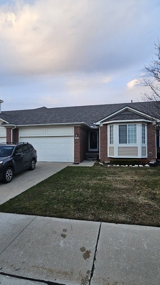 26123 Joanne Smith Ln, Chesterfield, MI 48051 - view of front facade with a garage, concrete driveway, a front yard, brick siding, and entry steps