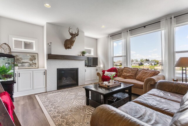 living room featuring healthy amount of natural light, a tiled fireplace, wood finished floors, and recessed lighting
