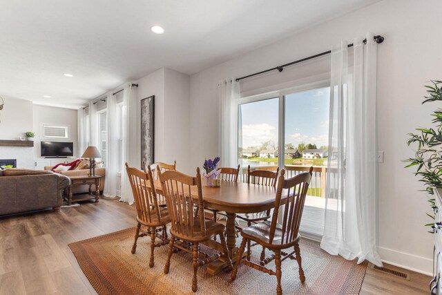 dining space with wood finished floors, recessed lighting, a glass covered fireplace, and baseboards