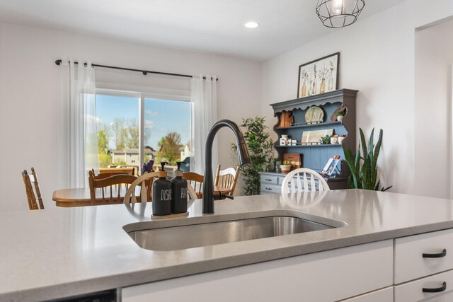 kitchen with a sink, light countertops, white cabinets, recessed lighting, and open shelves