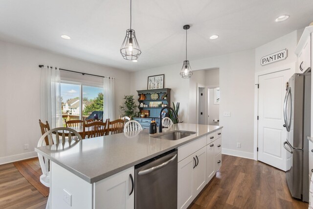 kitchen with a sink, appliances with stainless steel finishes, baseboards, an island with sink, and recessed lighting