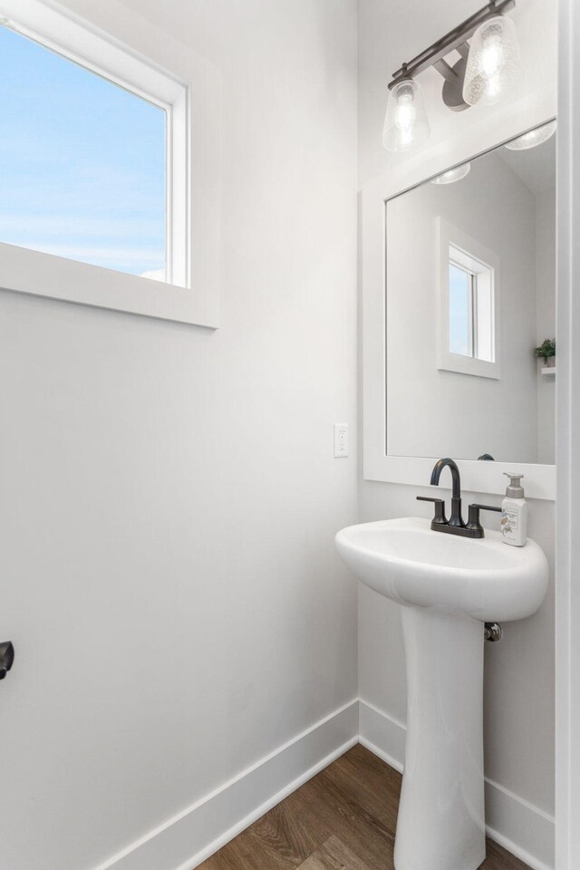 bathroom with baseboards, wood finished floors, and a sink