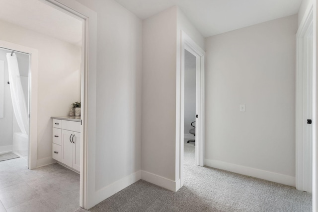 hallway featuring baseboards and light colored carpet