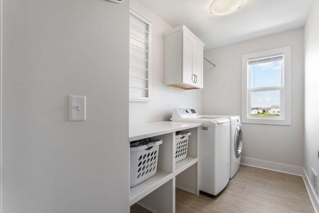 clothes washing area featuring cabinet space, washer and dryer, and baseboards