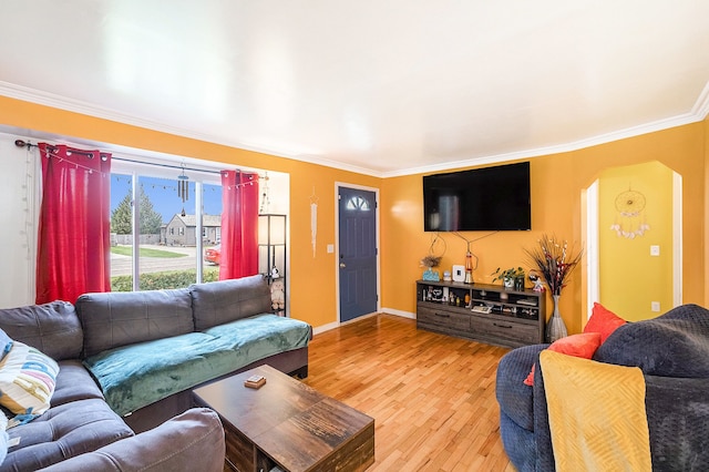 living area with crown molding, wood finished floors, arched walkways, and baseboards