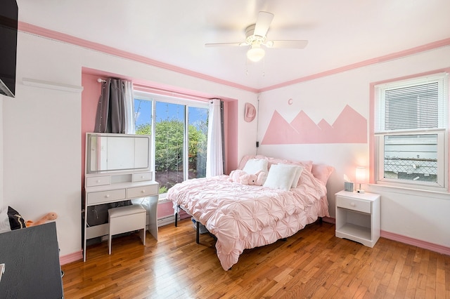 bedroom featuring light wood finished floors, baseboards, a ceiling fan, and ornamental molding