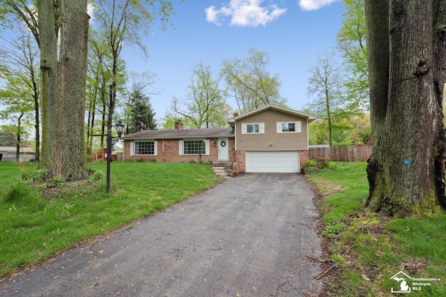 split level home featuring brick siding, asphalt driveway, an attached garage, and a chimney