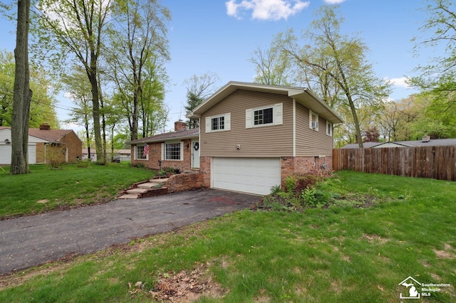 split level home featuring a garage, asphalt driveway, brick siding, and a chimney