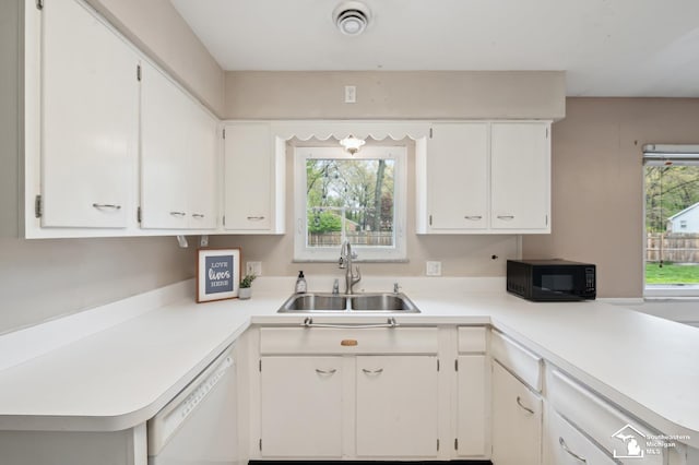 kitchen with a sink, dishwasher, black microwave, light countertops, and white cabinetry