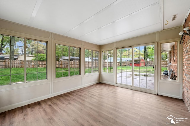 unfurnished sunroom with wood finished floors, baseboards, and a wooden deck