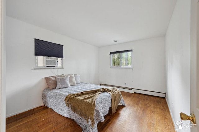 bedroom featuring a baseboard radiator, wood finished floors, cooling unit, and baseboards