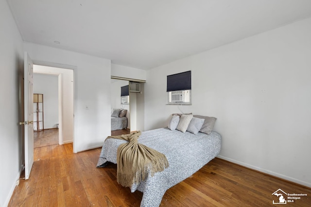 bedroom featuring light wood-style flooring, a closet, baseboards, and cooling unit