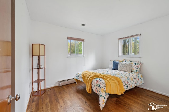 bedroom with a baseboard radiator, wood finished floors, and baseboards