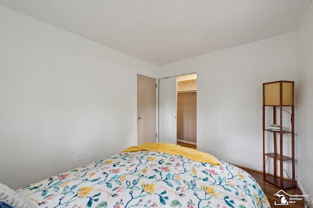 bedroom with dark wood-type flooring, baseboards, and a closet