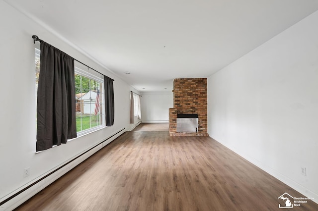 unfurnished living room featuring a baseboard radiator, wood finished floors, a brick fireplace, and baseboards