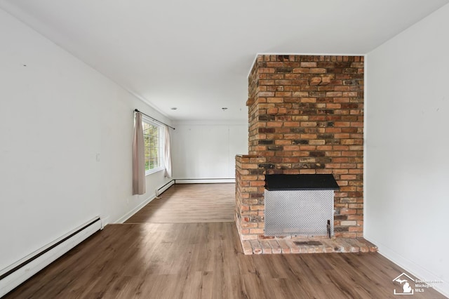unfurnished living room featuring baseboard heating, wood finished floors, a brick fireplace, and baseboards