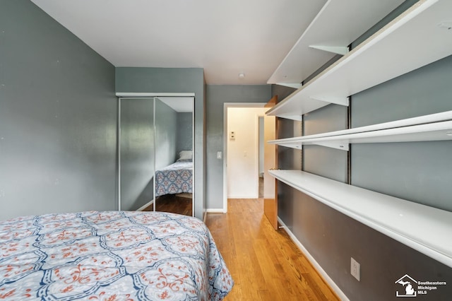 bedroom featuring a closet, light wood-style flooring, and baseboards