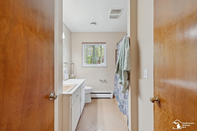 bathroom with a baseboard heating unit, toilet, vanity, and tile patterned floors