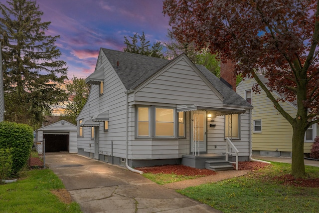 bungalow-style home with driveway, an outdoor structure, a shingled roof, and a detached garage