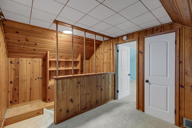 interior space featuring wooden walls, vaulted ceiling, and carpet flooring