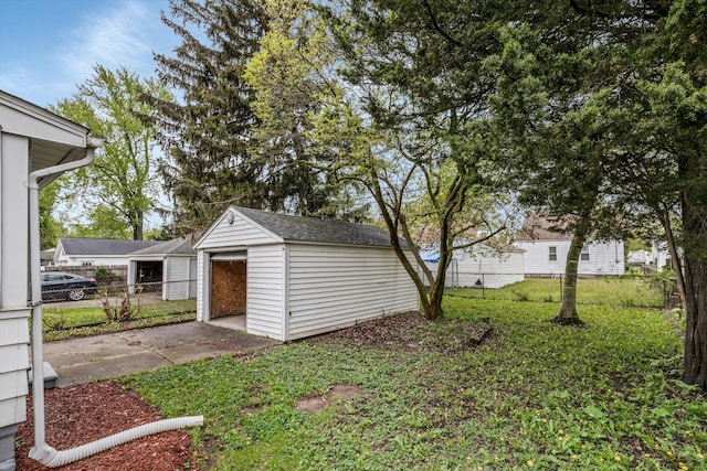 view of yard featuring a detached garage, an outbuilding, and fence