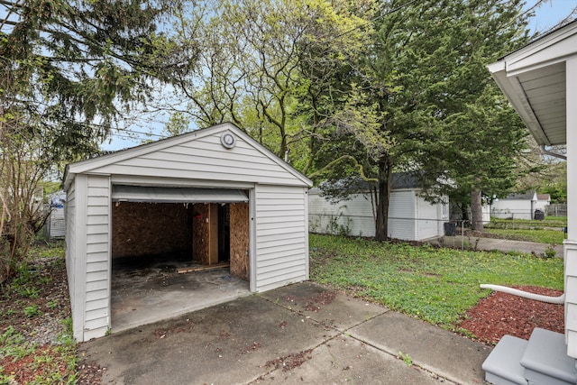 detached garage with concrete driveway and fence