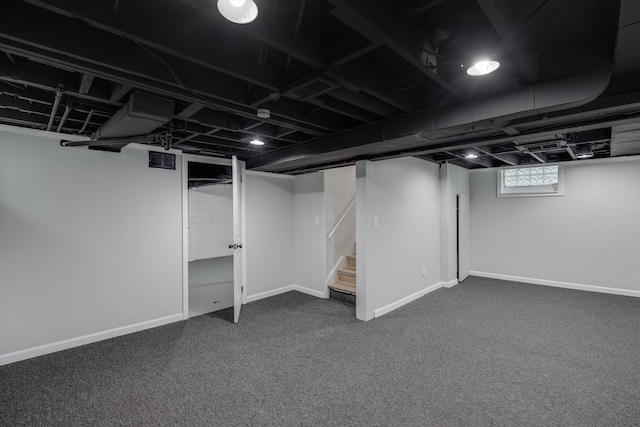 basement with dark colored carpet, stairway, and baseboards