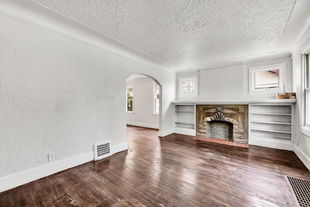 9171 Bishop St, Detroit, MI 48224 - unfurnished living room featuring a textured ceiling, arched walkways, a textured wall, wood finished floors, and baseboards